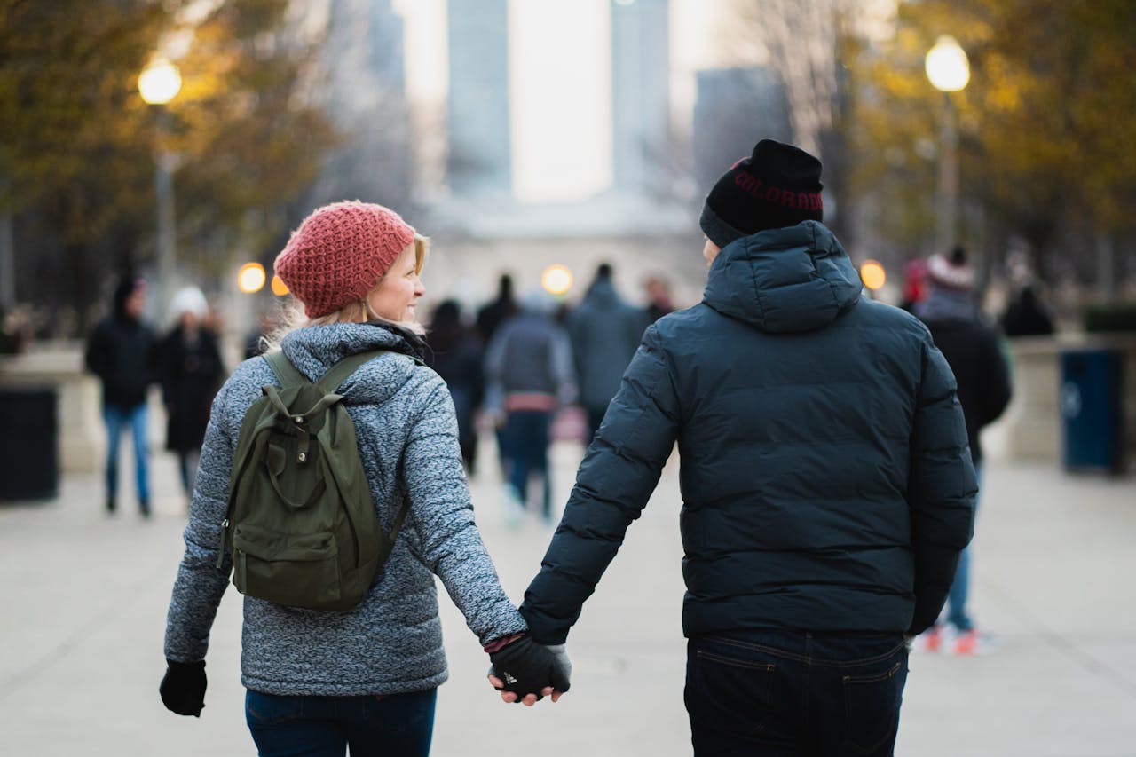 A couple holds hands on a winter day in an urban park, capturing warmth and connection.